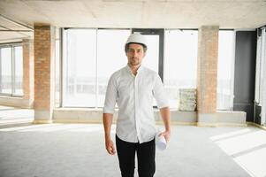 Portrait of an architect builder studying layout plan of the rooms, serious civil engineer working with documents on construction site, building and home renovation, professional foreman at work. photo