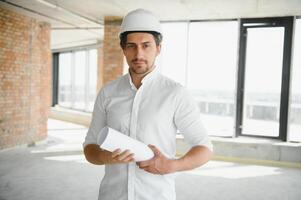Portrait of man architect at building site. Confident construction manager wearing hardhat. Successful mature civil engineer at construction site with copy space. photo
