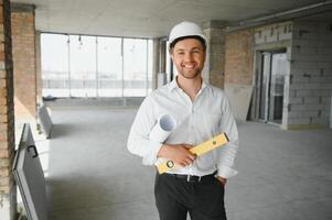 Portrait of man architect at building site. Confident construction manager wearing hardhat. Successful mature civil engineer at construction site with copy space. photo
