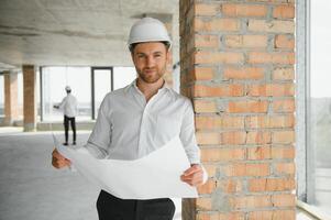 Portrait of man architect at building site. Confident construction manager wearing hardhat. Successful mature civil engineer at construction site with copy space. photo