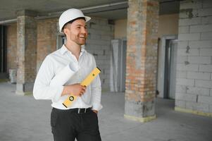 Portrait of an architect builder studying layout plan of the rooms, serious civil engineer working with documents on construction site, building and home renovation, professional foreman at work. photo