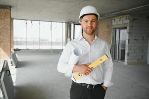 Portrait of an architect builder studying layout plan of the rooms, serious civil engineer working with documents on construction site, building and home renovation, professional foreman at work. photo