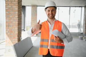 Portrait of an architect builder studying layout plan of the rooms, serious civil engineer working with documents on construction site, building and home renovation, professional foreman at work. photo