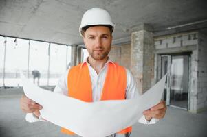 Portrait of an architect builder studying layout plan of the rooms, serious civil engineer working with documents on construction site, building and home renovation, professional foreman at work. photo