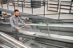 A man with a shopping cart on an escalator in a hardware store. photo