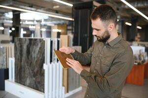 Man choosing tile among different samples in store photo