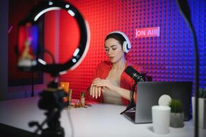 Beauty blogger woman filming daily make-up routine tutorial near camera on tripod photo