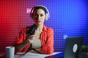 Young attractive woman blogger or vlogger looking at camera and talking on shooting with technology photo