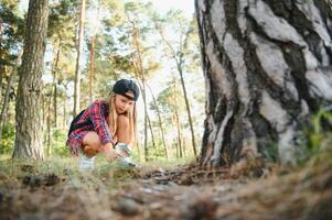 Image of cute kid with magnifying glass exploring the nature outdoors. Adorable little girl playing in the forest with magnifying glass. Curious child looking through magnifier on a sunny day in park. photo