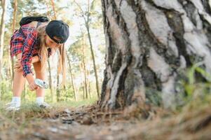 Rear view image of cute little girl exploring the nature with magnifying glass outdoor. Child playing in the forest with magnifying glass. photo