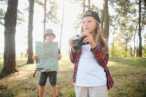 Happy excited school children with backpacks in casual clothes enjoying walk in forest on sunny autumn day, two active kids boy and girl running and playing together during camping trip in nature. photo