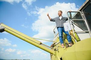 Harvester machine driver climbing into a cab to harvest his wheat field. Farmer getting in combine on ladder holding railing. Agronomist. Rancher after harvesting work photo