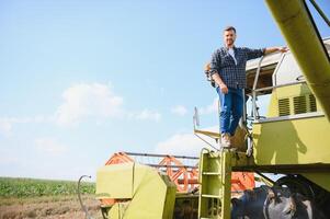 Harvester machine driver climbing into a cab to harvest his wheat field. Farmer getting in combine on ladder holding railing. Agronomist. Rancher after harvesting work photo