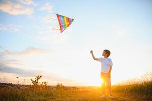 Boy is running with a kite during the day in the field photo