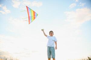 Boy is running with a kite during the day in the field photo