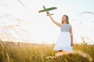 Happy kid with toy plane is playing at sunset photo