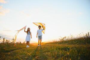 Children launch a kite in the field at sunset photo