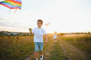 Children launch a kite in the field at sunset photo