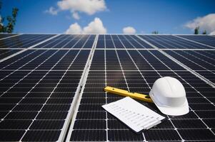 Solar cell contractor document with orange engineering team helmet on solar cells panels. Renewable energy and ecology concept. photo