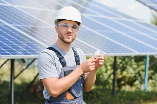 Technical expert in solar photovoltaic panels, remote control performs routine actions to monitor the system using clean renewable energy in the hand a light bulb. photo