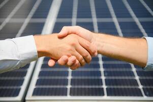 Workers shaking hands on a background of solar panels on solar power plant photo
