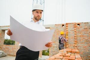 Engineering Consulting People on construction site holding blueprint in his hand. Building inspector. Construction site check drawing and business workflow of new building. photo