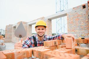 Busy with brick wall. Construction worker in uniform and safety equipment have job on building. photo