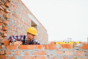 Installing brick wall. Construction worker in uniform and safety equipment have job on building photo