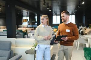 Smiling female customer looking while listening to employee discussing about sofa at store photo