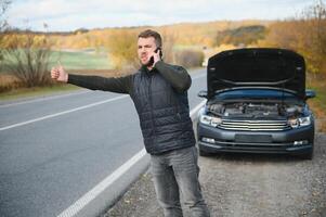 A man calls a phone number to talk to a mechanic. The car broke down on the roadside. The concept for fix, help, problem, repair. blurred background. photo