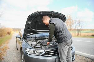 driver trying to figure out how to fix broken down car with red triangle to warn other road users photo