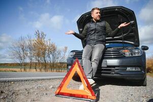 Man with broken car in the middle of the road. photo