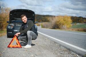 Man with broken car in the middle of the road. photo