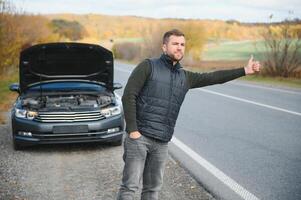 Man with broken car in the middle of the road. photo