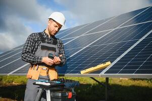 Professional worker installing solar panels on the metal construction, using different equipment, wearing helmet. Innovative solution for energy solving. Use renewable resources. Green energy. photo