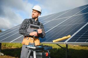 Professional worker installing solar panels on the metal construction, using different equipment, wearing helmet. Innovative solution for energy solving. Use renewable resources. Green energy. photo