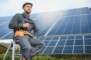 Professional worker installing solar panels on the metal construction, using different equipment, wearing helmet. Innovative solution for energy solving. Use renewable resources. Green energy. photo
