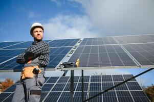 Professional worker installing solar panels on the metal construction, using different equipment, wearing helmet. Innovative solution for energy solving. Use renewable resources. Green energy. photo