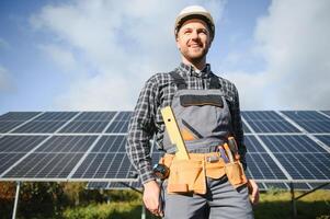 Professional worker installing solar panels on the metal construction, using different equipment, wearing helmet. Innovative solution for energy solving. Use renewable resources. Green energy. photo