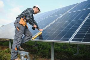 Professional worker installing solar panels on the metal construction, using different equipment, wearing helmet. Innovative solution for energy solving. Use renewable resources. Green energy. photo