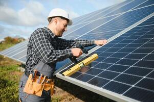 Professional worker installing solar panels on the metal construction, using different equipment, wearing helmet. Innovative solution for energy solving. Use renewable resources. Green energy. photo