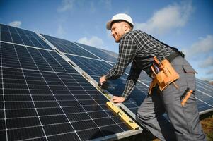 Professional worker installing solar panels on the metal construction, using different equipment, wearing helmet. Innovative solution for energy solving. Use renewable resources. Green energy. photo