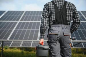 Professional worker installing solar panels on the metal construction, using different equipment, wearing helmet. Innovative solution for energy solving. Use renewable resources. Green energy. photo