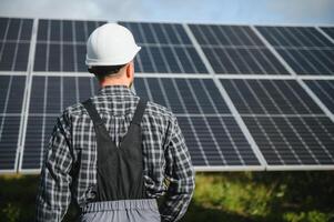Professional worker installing solar panels on the metal construction, using different equipment, wearing helmet. Innovative solution for energy solving. Use renewable resources. Green energy. photo
