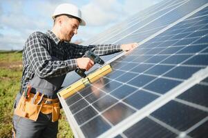 Professional worker installing solar panels on the metal construction, using different equipment, wearing helmet. Innovative solution for energy solving. Use renewable resources. Green energy. photo