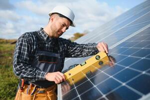 Professional worker installing solar panels on the metal construction, using different equipment, wearing helmet. Innovative solution for energy solving. Use renewable resources. Green energy. photo
