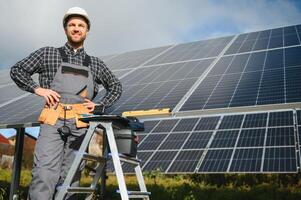 Professional worker installing solar panels on the metal construction, using different equipment, wearing helmet. Innovative solution for energy solving. Use renewable resources. Green energy. photo