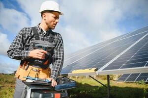Professional worker installing solar panels on the metal construction, using different equipment, wearing helmet. Innovative solution for energy solving. Use renewable resources. Green energy. photo