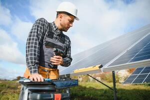 Professional worker installing solar panels on the metal construction, using different equipment, wearing helmet. Innovative solution for energy solving. Use renewable resources. Green energy. photo