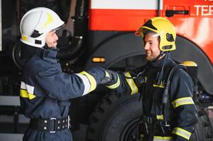 Portrait of two heroic fireman in protective suit and helmet. photo
